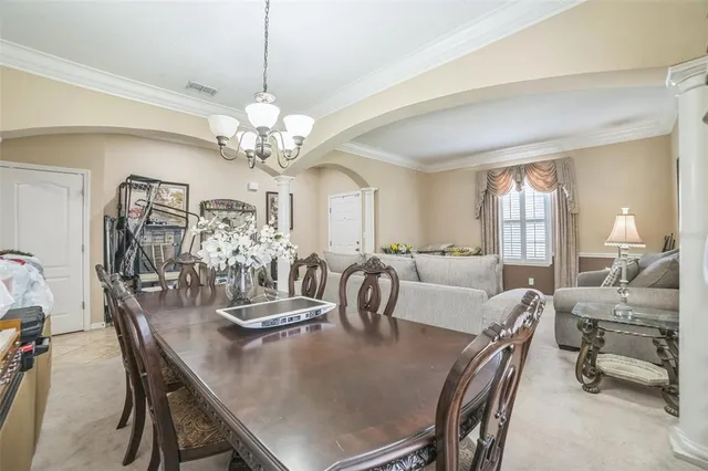 a view of a dining room with furniture a chandelier and large windows