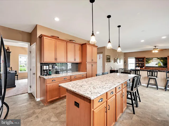 a large kitchen with kitchen island a stove a sink a center island and wooden cabinets
