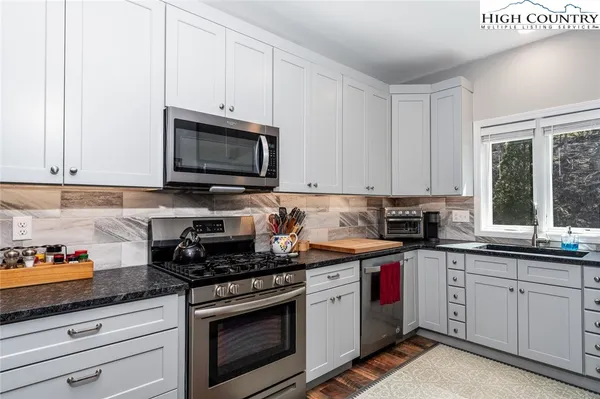 a kitchen with granite countertop white cabinets sink and stainless steel appliances