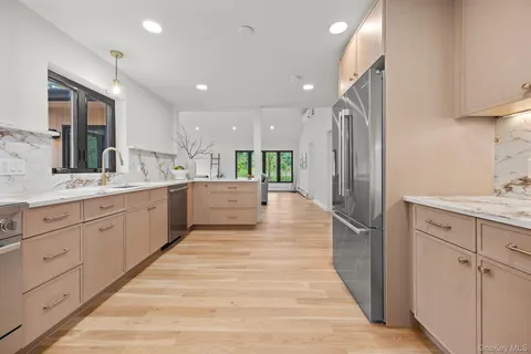 a large white kitchen with a sink stainless steel appliances and cabinets