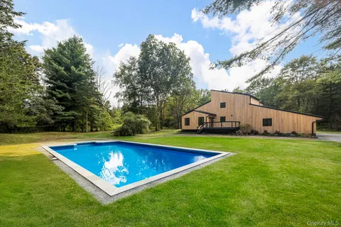 a view of pool with lawn chairs and plants