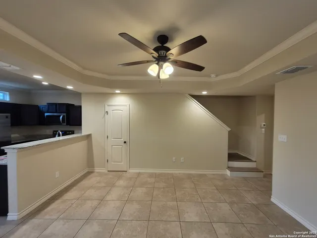 a view of an empty room with kitchen appliances and a ceiling fan