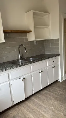 a kitchen with granite countertop white cabinets and sink