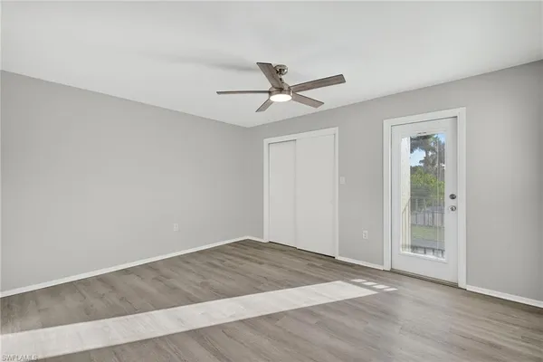 an empty room with wooden floor and ceiling fan