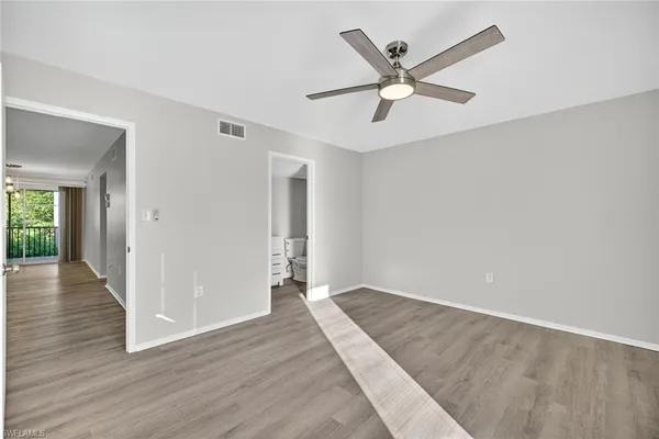 an empty room with wooden floor and ceiling fan