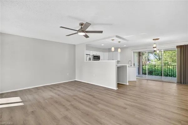 a view of a big room with wooden floor a ceiling fan and windows