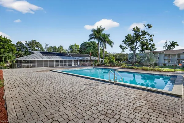 a view of swimming pool with seating space and trees in the background
