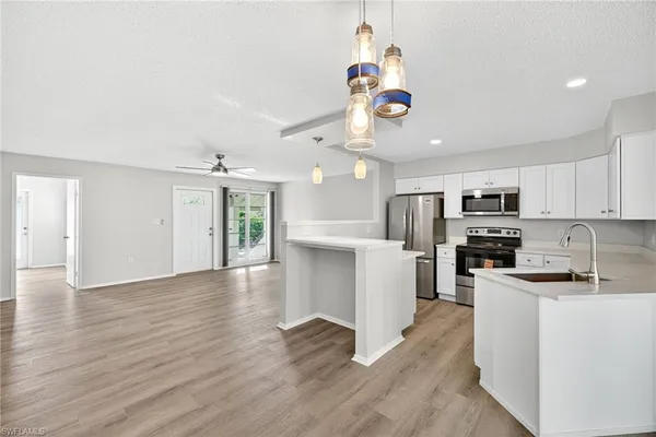 a kitchen with stainless steel appliances granite countertop a refrigerator a stove top oven a sink dishwasher and a dining table with wooden floor