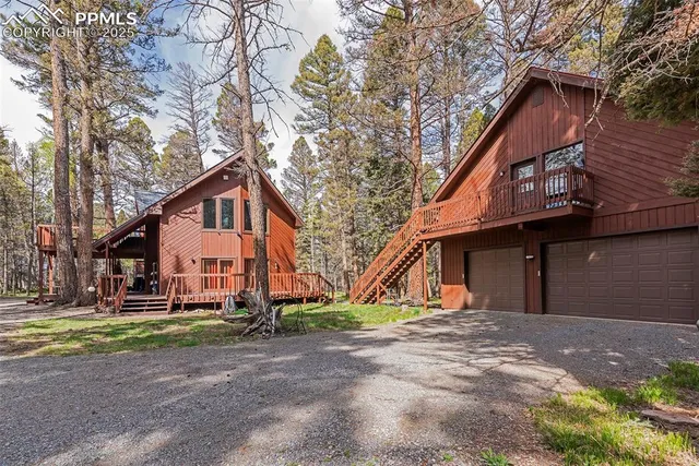a view of a house with a yard and large trees