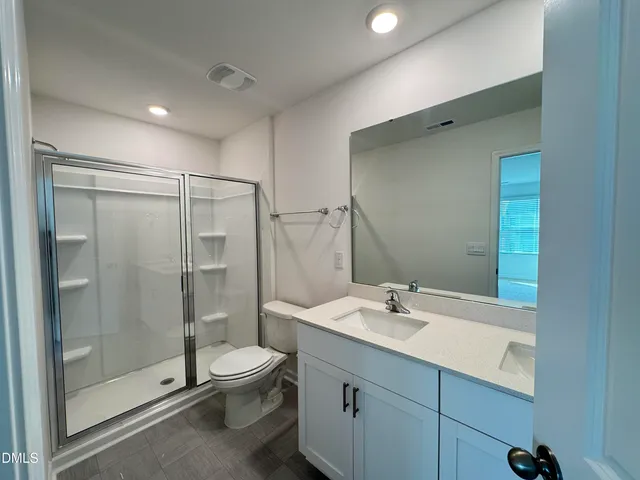 a bathroom with a shower sink mirror and toilet
