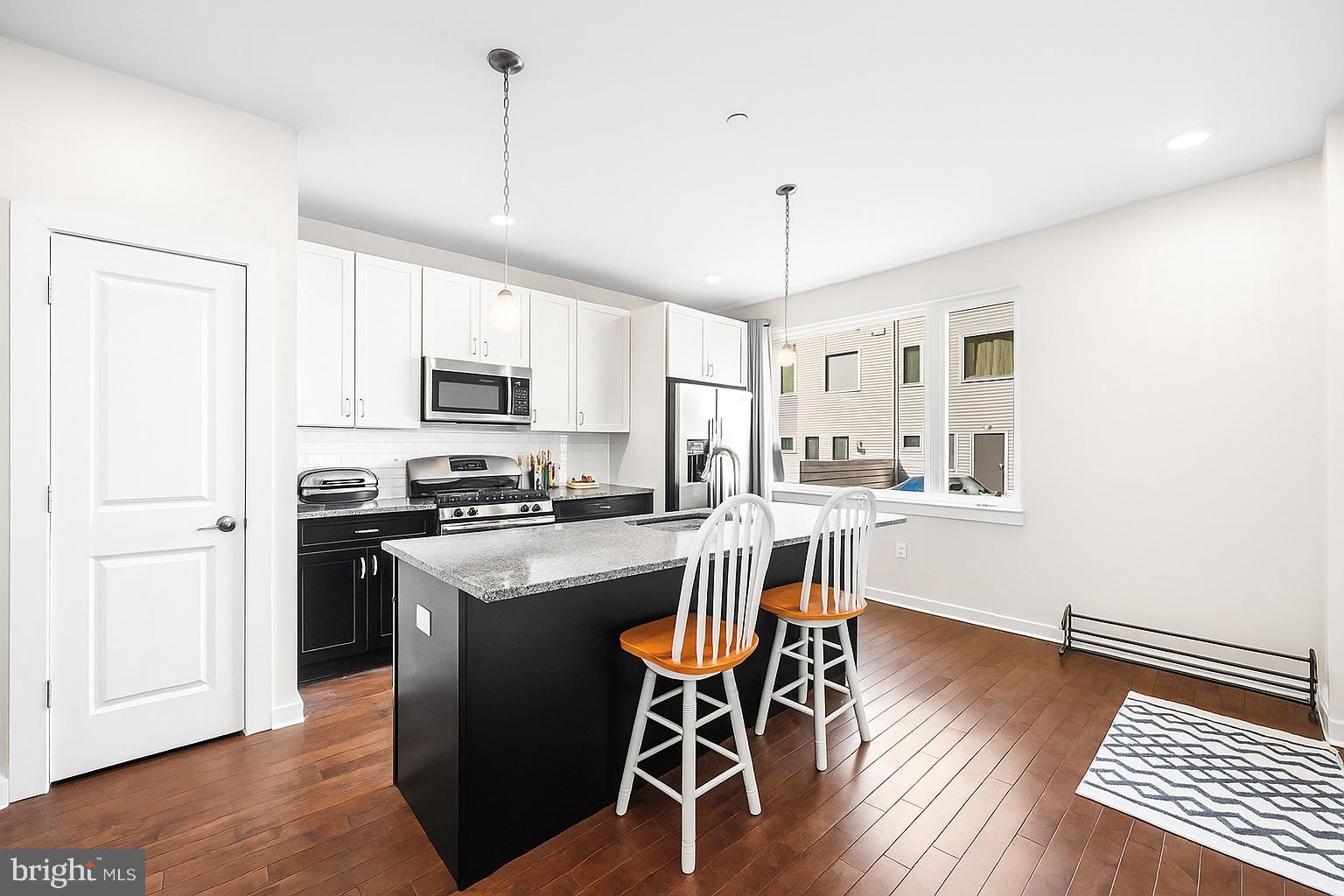 1640 North 5th Court, Unit 29A Philadelphia, PA 19122 - Photo 2 of 21 a kitchen with stainless steel appliances granite countertop a stove top oven a refrigerator a dining table and chairs with wooden floor