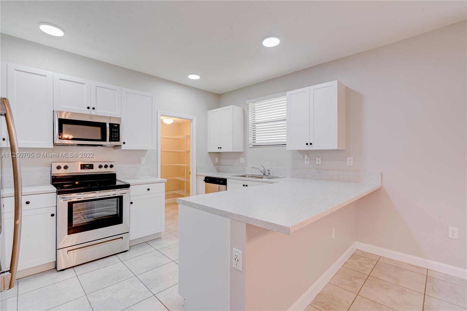 124 Northeast 25th Avenue Homestead, FL 33033 - Photo 5 of 32 a kitchen with a sink white cabinets and stainless steel appliances