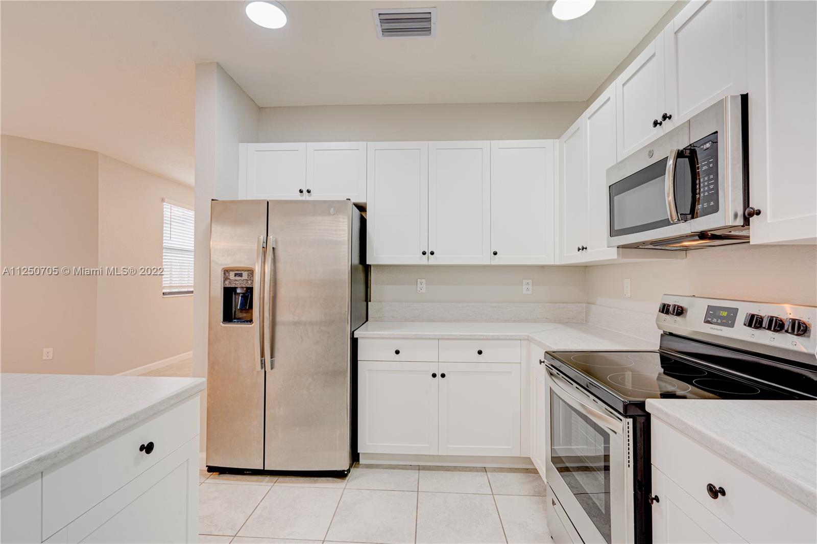 124 Northeast 25th Avenue Homestead, FL 33033 - Photo 7 of 32 a kitchen with stainless steel appliances a refrigerator stove and microwave