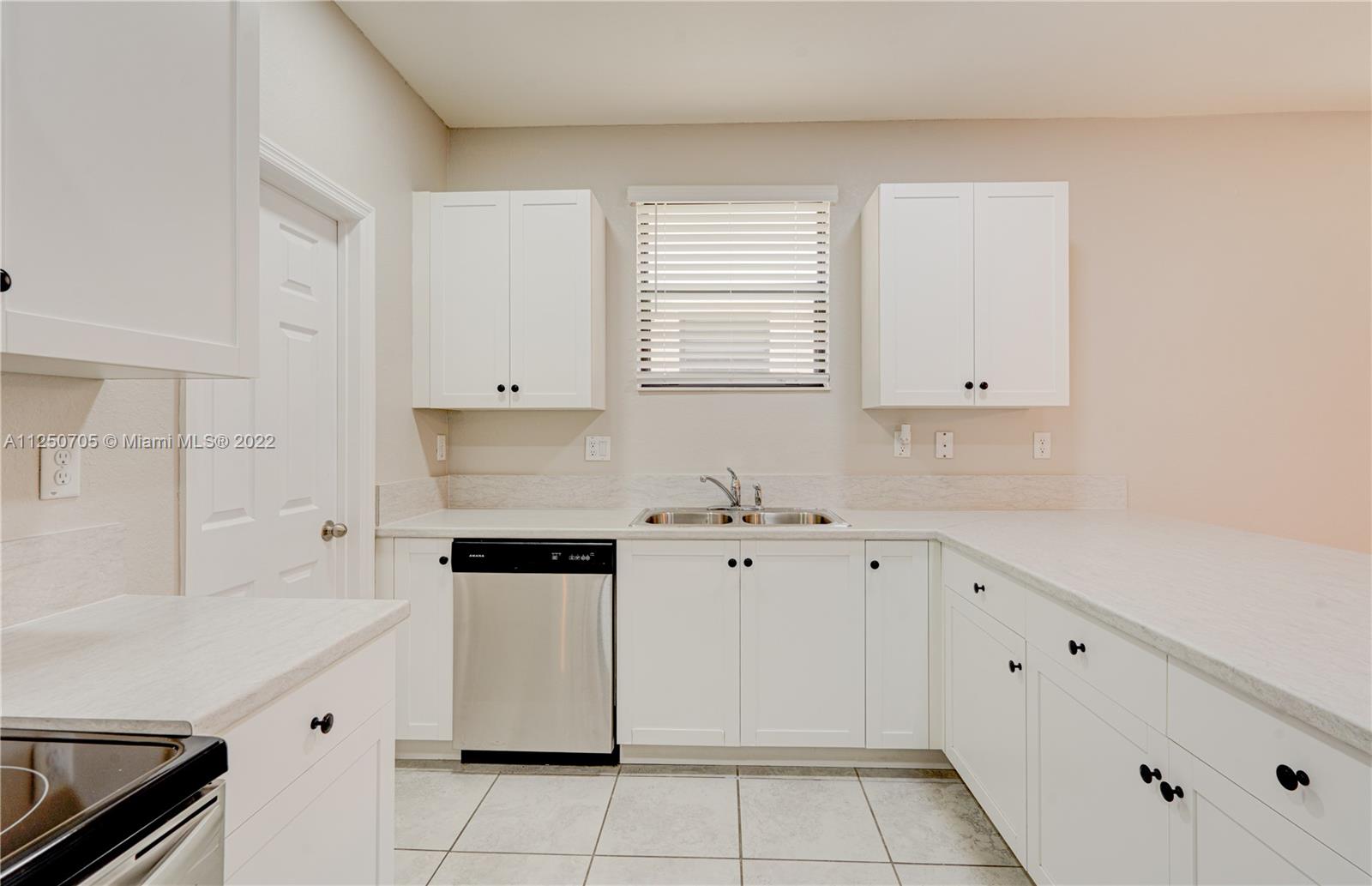 124 Northeast 25th Avenue Homestead, FL 33033 - Photo 8 of 32 a kitchen with white cabinets and window