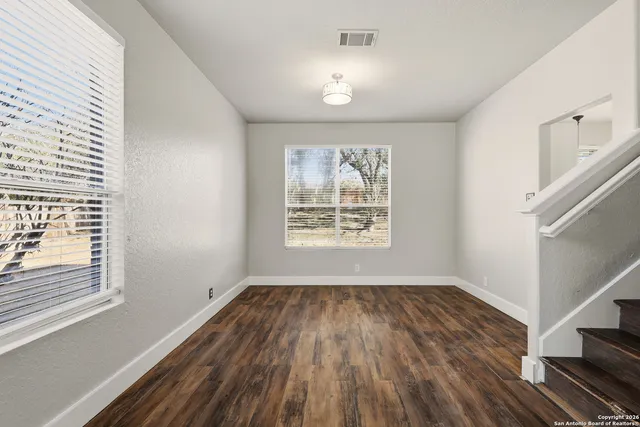 a view of empty room with wooden floor and fan