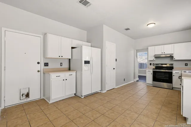 a kitchen with granite countertop a refrigerator and a stove top oven