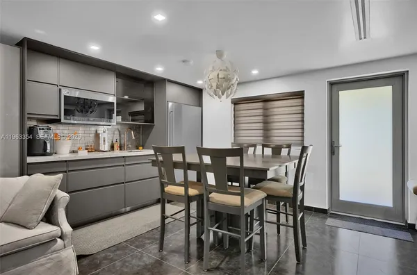 a kitchen with stainless steel appliances kitchen island granite countertop a dining table chairs and a refrigerator