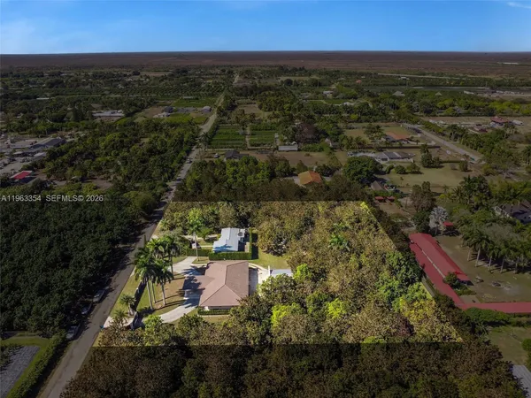 an aerial view of residential houses with outdoor space and trees