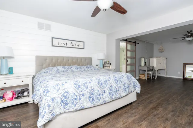 a bedroom with a bed and dresser with wooden floor
