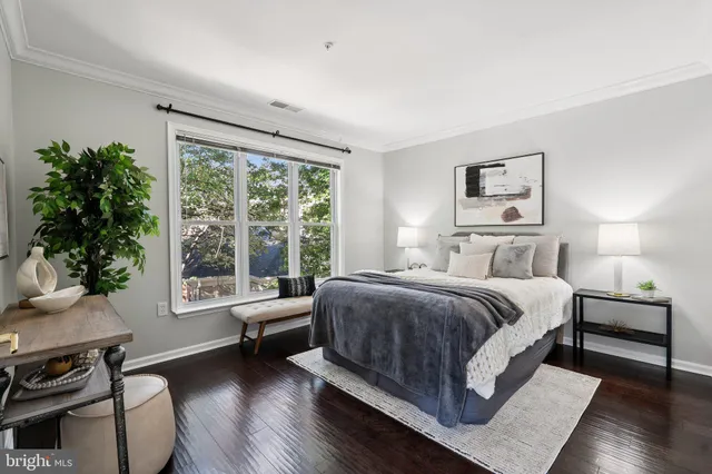 a spacious bedroom with a bed a couch and a large window with wooden floor