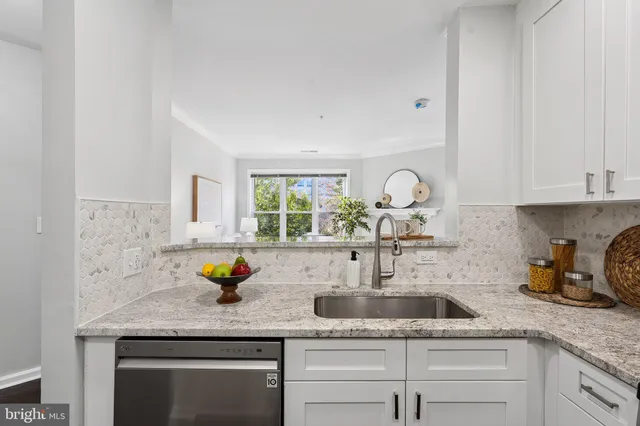 a kitchen with white cabinets and sink