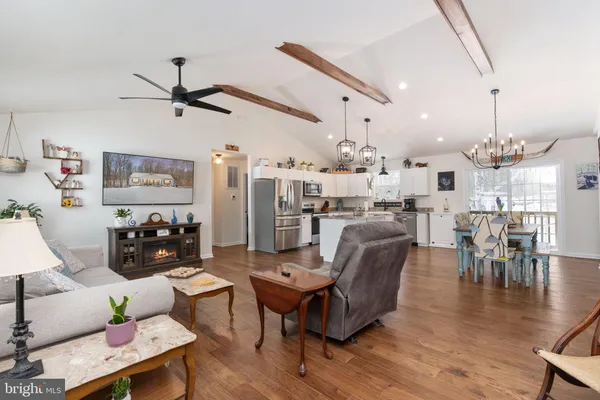 a living room with furniture kitchen view and a chandelier