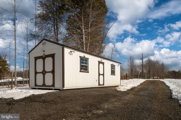 a backyard of a house with large trees and wooden fence