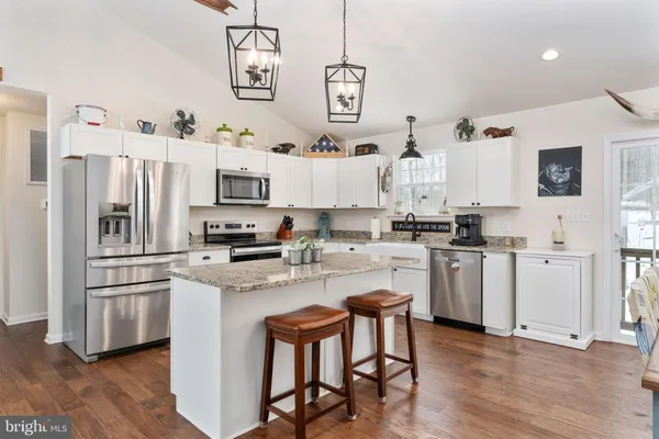 a kitchen with cabinets stainless steel appliances and wooden floor