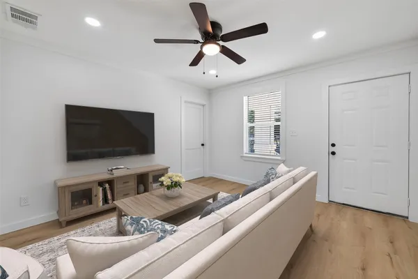an empty room with wooden floor ceiling fan and windows