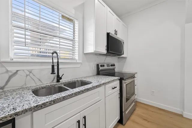 a kitchen with granite countertop a stove a sink and a microwave