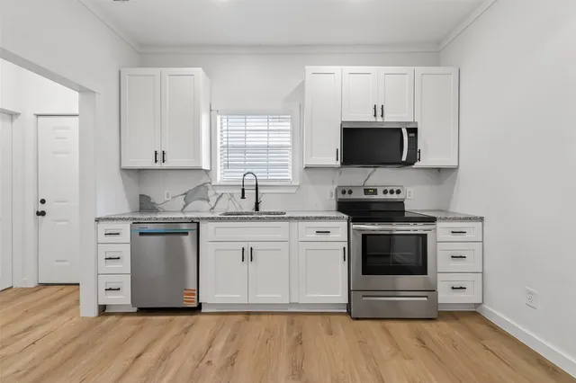 a kitchen with granite countertop white cabinets stainless steel appliances and a sink