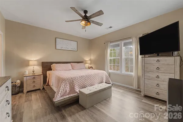 a spacious bedroom with a bed and a flat screen tv