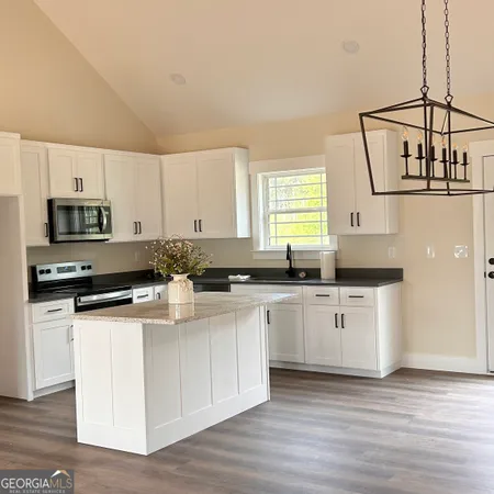 a kitchen with stainless steel appliances white cabinets a sink a stove a microwave and wooden floors