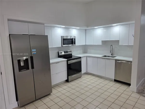 a kitchen with a refrigerator sink and cabinets