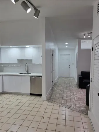 a large white kitchen with a stove top oven a sink and a microwave