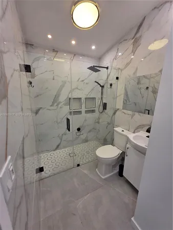 a bathroom with a toilet sink vanity granite and shower