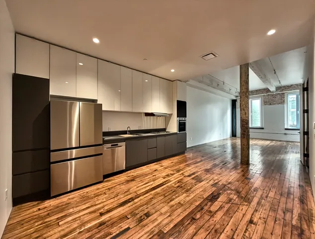 a kitchen with granite countertop a refrigerator and a stove top oven