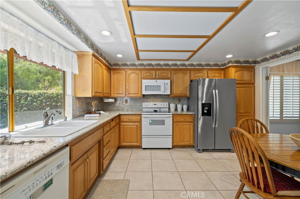 28784 Eagleton Street Agoura Hills, CA 91301 - Photo 15 of 48 a kitchen with stainless steel appliances granite countertop a refrigerator a sink dishwasher a stove and a dining table with wooden cabinet
