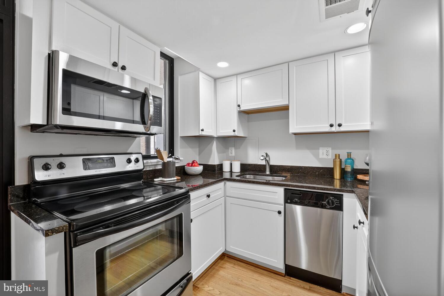 1701 16th Street Northwest, Unit 440 Washington, DC 20009 - Photo 11 of 31 a kitchen with cabinets stainless steel appliances and wooden floor