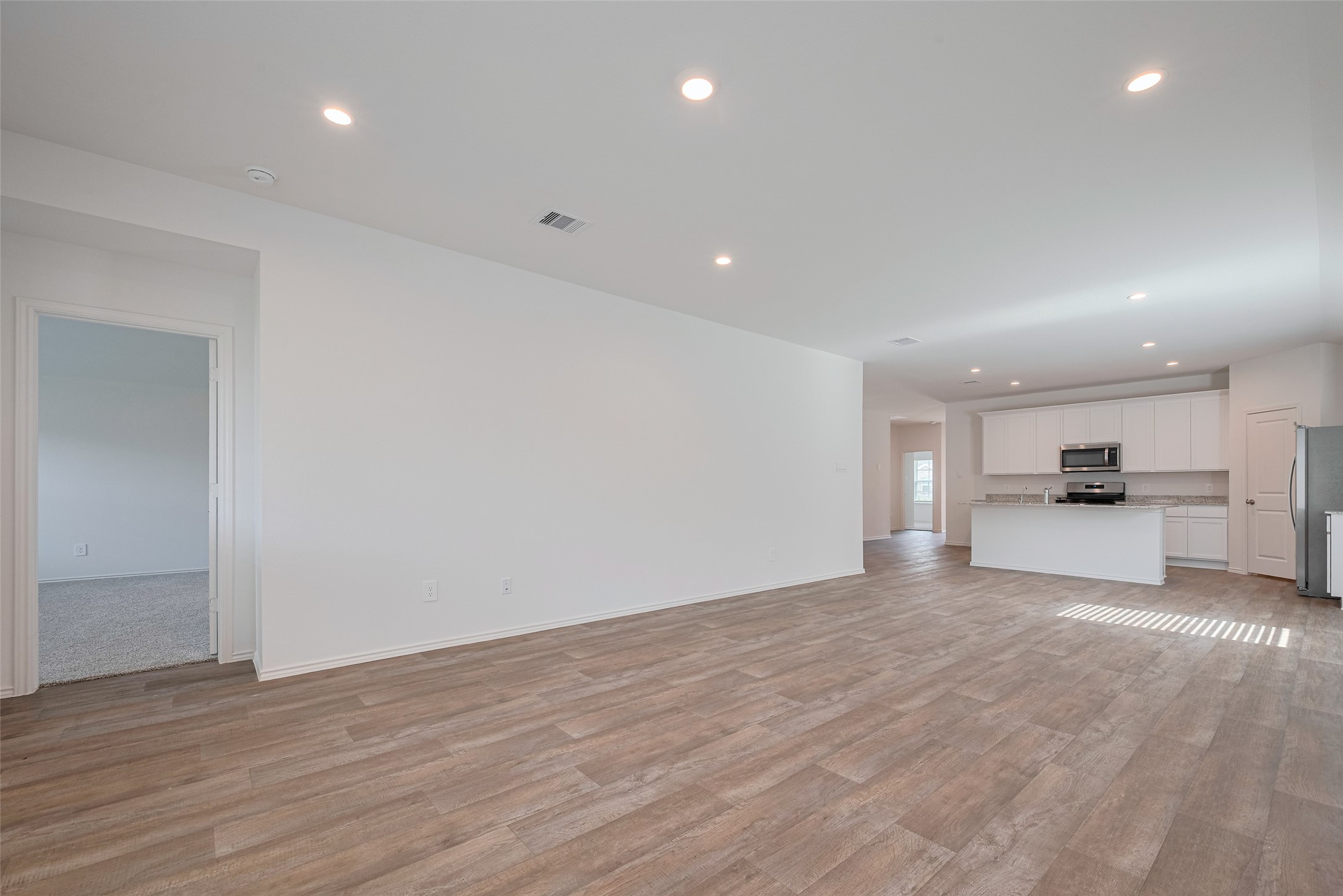 30842 Brightwell Bend Fulshear, TX 77441 - Photo 11 of 31 Spacious open-concept family room flowing seamlessly into dining area and kitchen. Wood-look flooring and recessed lighting throughout. Large open layout perfect for entertaining