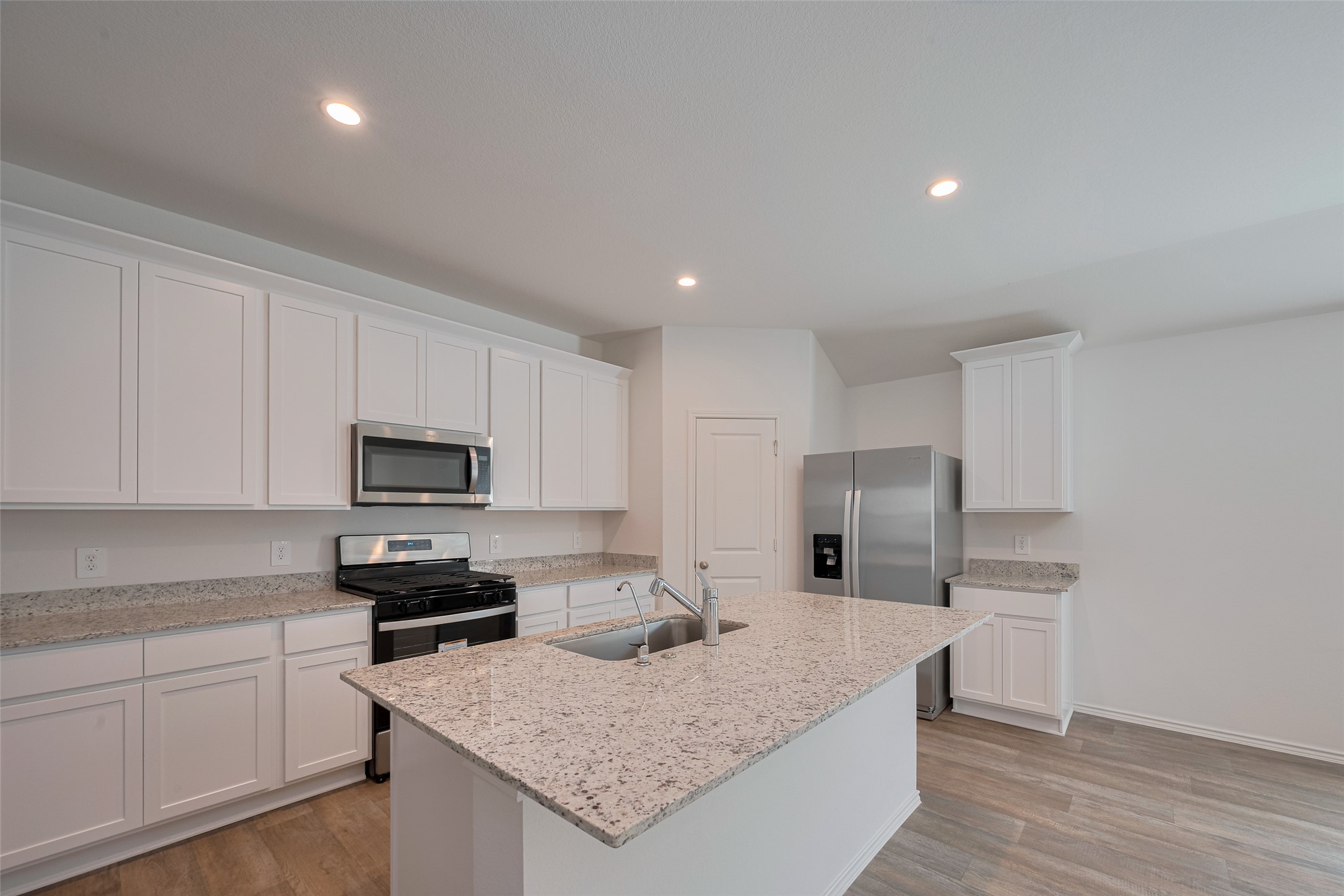 30842 Brightwell Bend Fulshear, TX 77441 - Photo 13 of 31 Bright kitchen with granite counters, white cabinets, and a large island with sink. Stainless steel appliances, gas range, and ample storage make this space perfect for everyday living and entertaining.