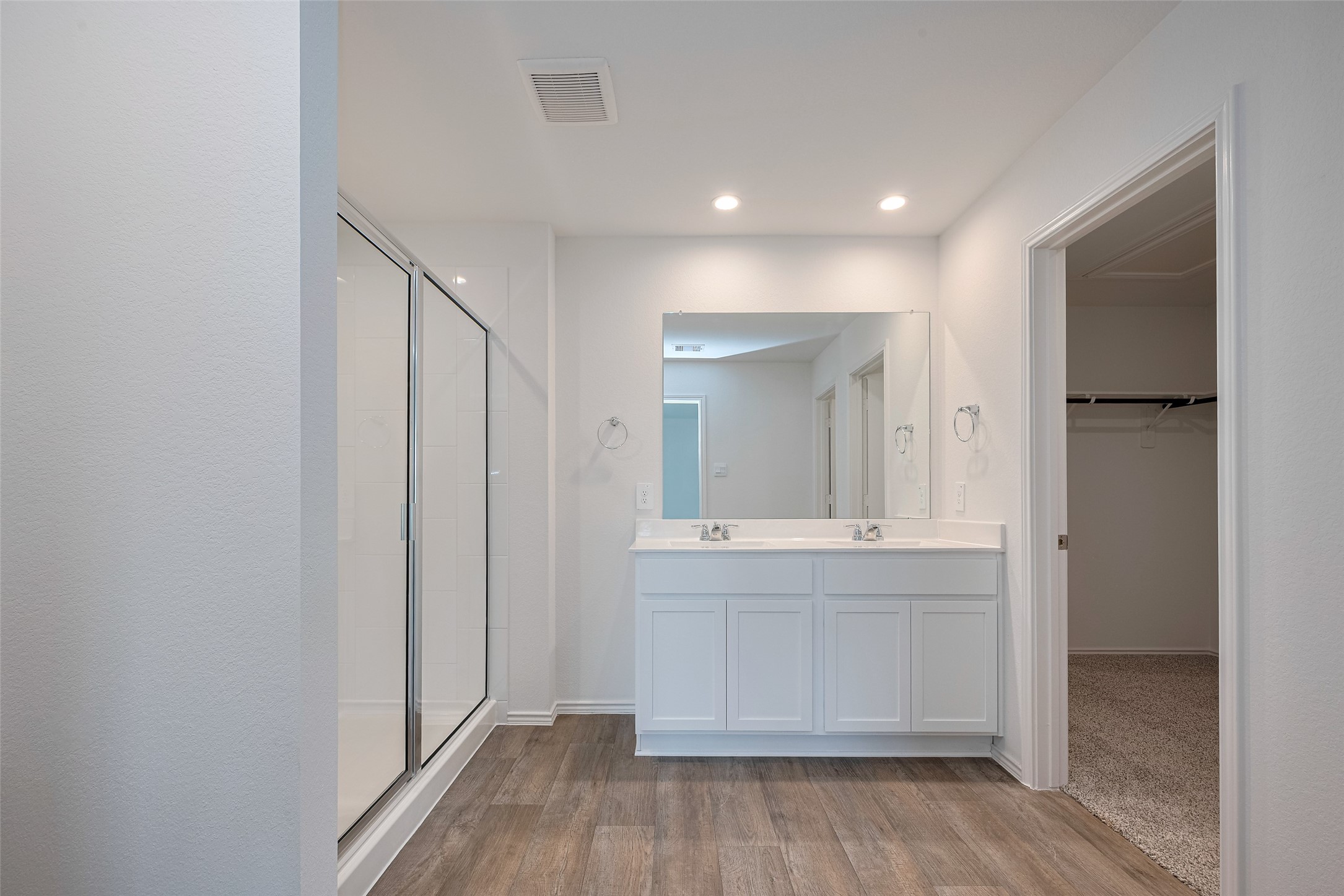30842 Brightwell Bend Fulshear, TX 77441 - Photo 26 of 31 The primary bathroom features a dual-sink vanity with white cabinetry, a broad mirror, and an enclosed shower with nearby open shelving. A connecting full entry closet adds everyday convenience.