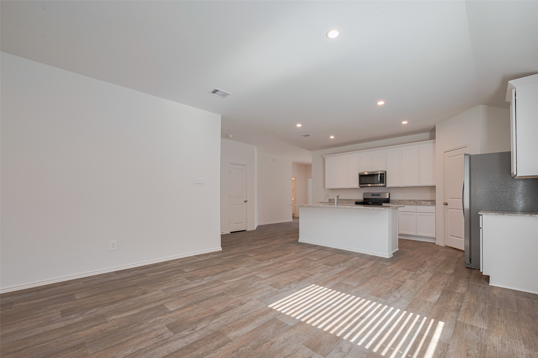 30842 Brightwell Bend Fulshear, TX 77441 - Photo 6 of 31 Open-concept family room flowing into dining area and kitchen. Wood-look flooring, recessed lighting, and neutral paint throughout. Spacious layout with natural light