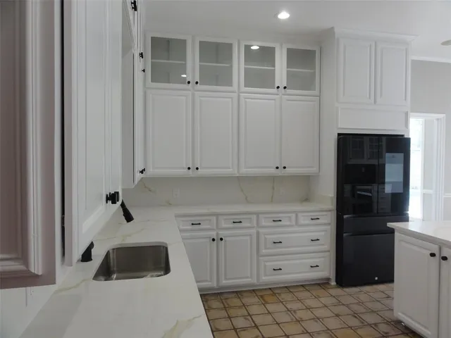 a kitchen with white cabinets and sink