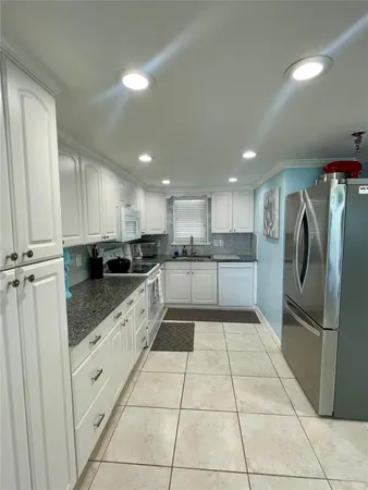 a large white kitchen with a stove a refrigerator and a sink