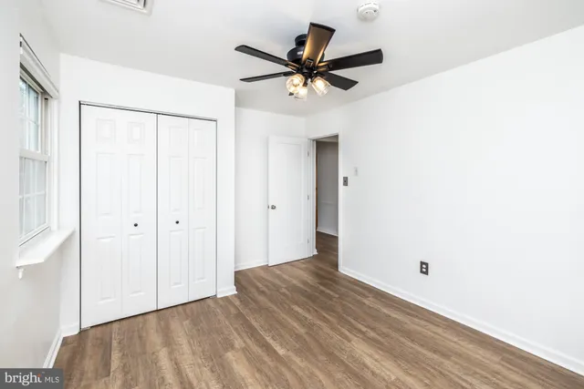 an empty room with wooden floor closet and windows