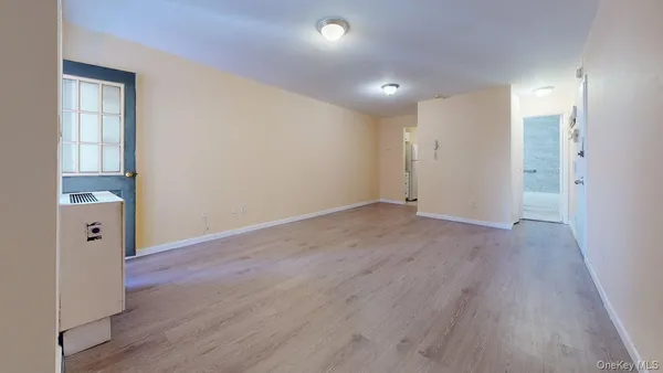 a view of an empty room with wooden floor and a window