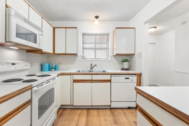 a kitchen with granite countertop white cabinets sink and appliances
