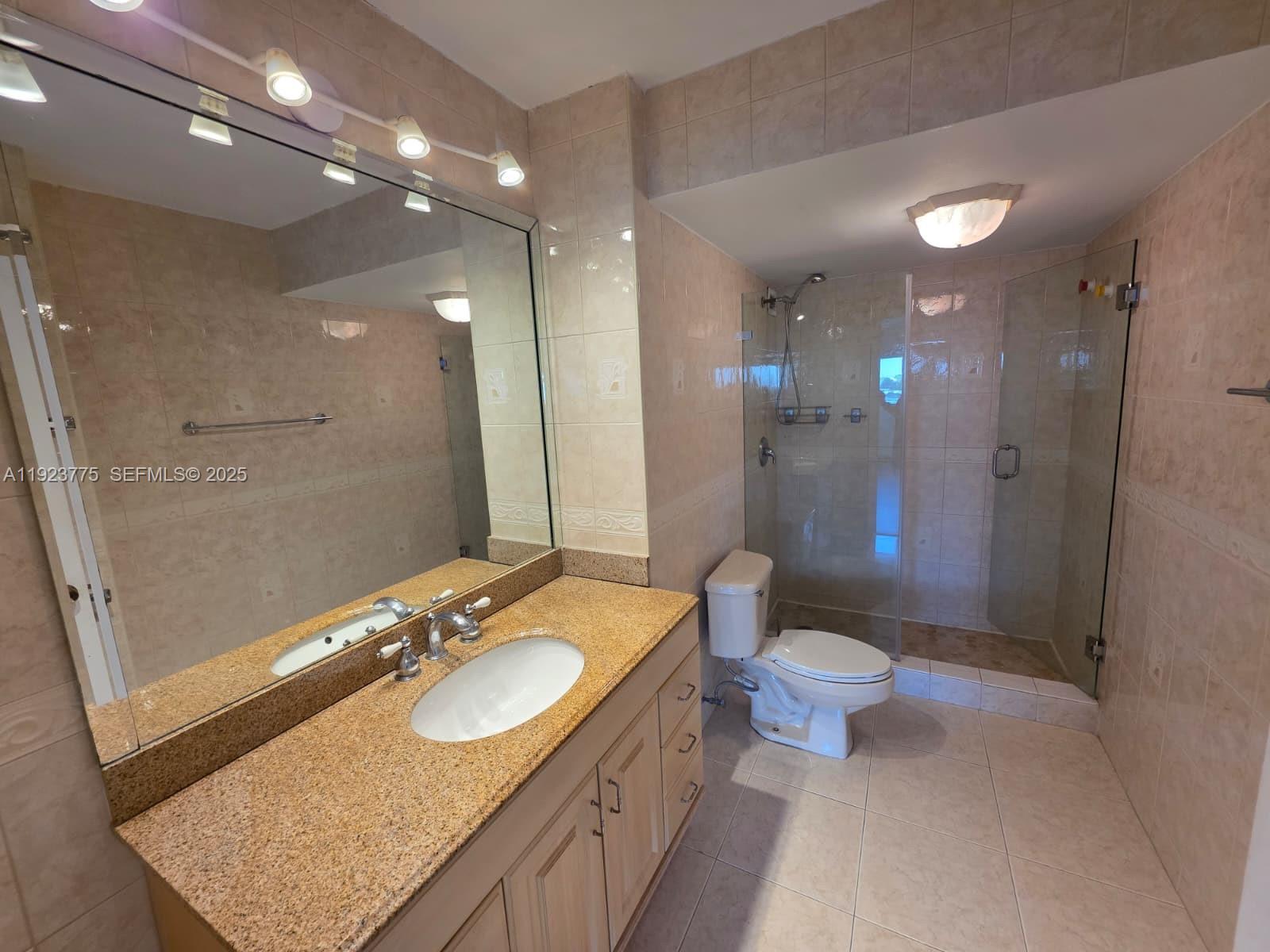 7135 Collins Avenue, Unit 725 Miami Beach, FL 33141 - Photo 11 of 21 a bathroom with a granite countertop sink a toilet a mirror and shower