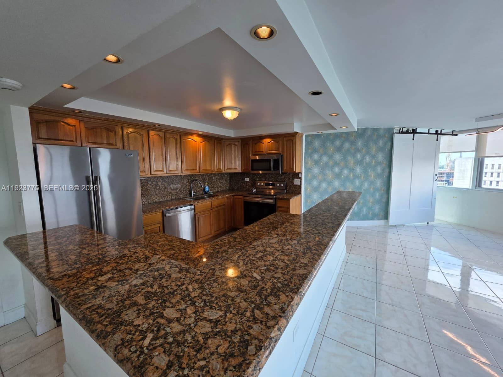 7135 Collins Avenue, Unit 725 Miami Beach, FL 33141 - Photo 6 of 21 a kitchen with stainless steel appliances granite countertop a sink and a refrigerator